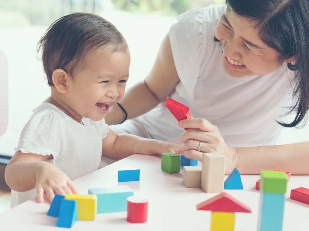 An Asian mother and her toddler playing with Blocks.